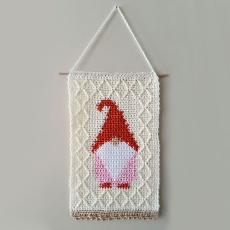Instead of placing gnomes all over your surfaces, you could also opt for this lovely gnome wall hanging. This hanging is made using single crochet stitches and using the intarsia crochet colorwork technique and then framed with a textured lattice stitch. It is easily customizable according to the mood and vibe you are going for by simply swapping out the colors.