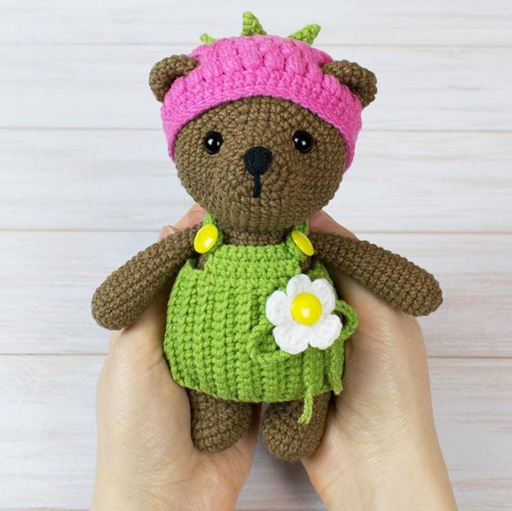 This lovely teddy bear reminds me of spring, with its warm meadows and bright sunlight. It looks like it's ready for flower picking or a picnic in the flower beds.