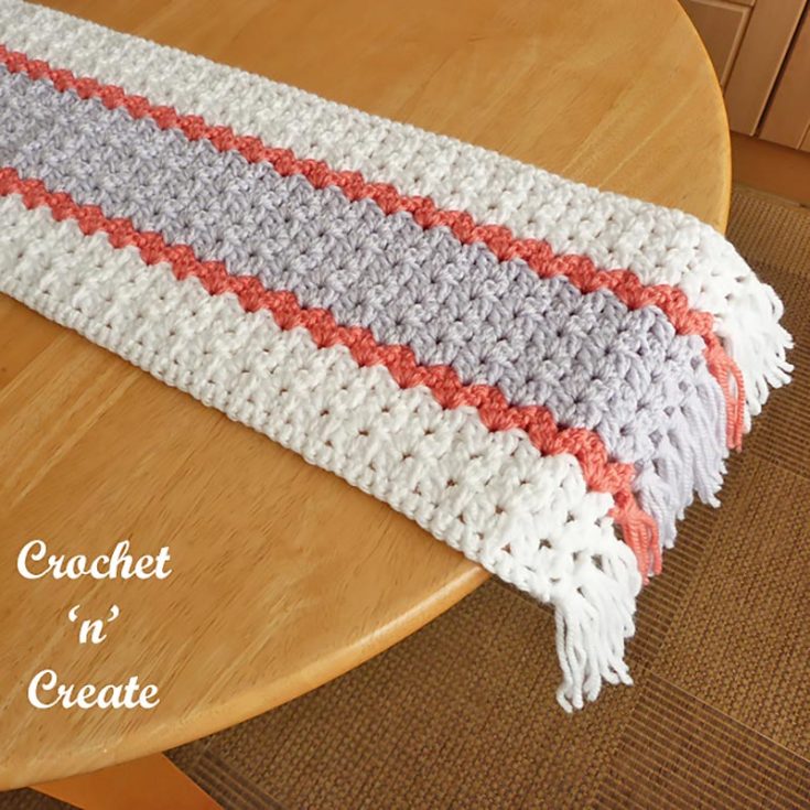 These cluster V-stitches make pretty rows of eyelets in this three-color table runner. Using worsted-weight yarn makes this table runner nice, thick, and sturdy enough to lay permanently on your surface.