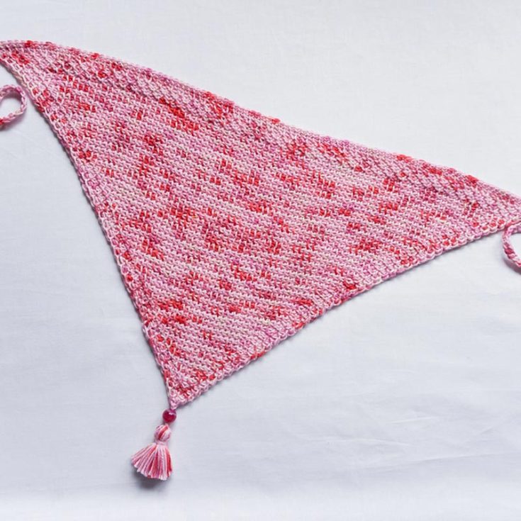 Make this Tunisian crochet pattern for a triangle-shaped bandana with some cool ties. This beginner-friendly pattern uses lightweight yarn and has a border to help prevent curling.