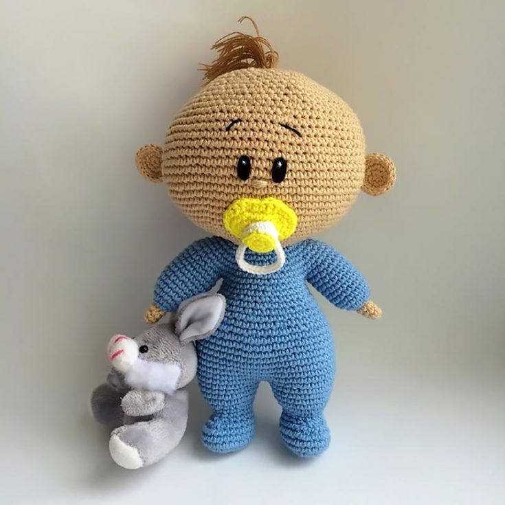 Here is another version of a crochet baby doll pattern. This baby has a onesie, a tuft of hair, and a cute little pacifier! It's ideal for beginners and intermediate crocheters as well. The finished size for this dolly is 8" tall.