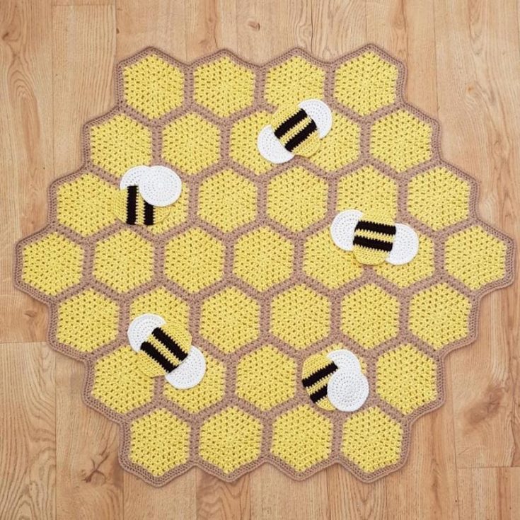Wrap yourself in the warmth of a honeycomb crochet bee blanket! It's a cute alternative to staying warm rather than just using a plain ol' blanket. Created with cute applique crochet bees, it adds a fun texture with a 3D effect. The finished size is 33" wide.
