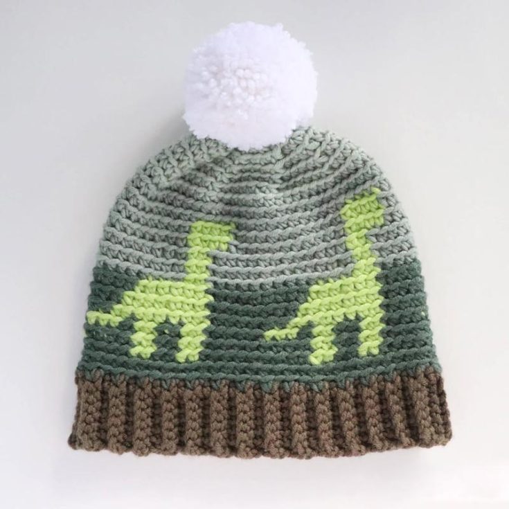 Learn how to make this cute crochet dinosaur hat for kids! It'll keep them warm during those chilly days, and you'll need to have your colorwork nailed down to make this pattern. The finished hat is about 18" suitable for toddlers.