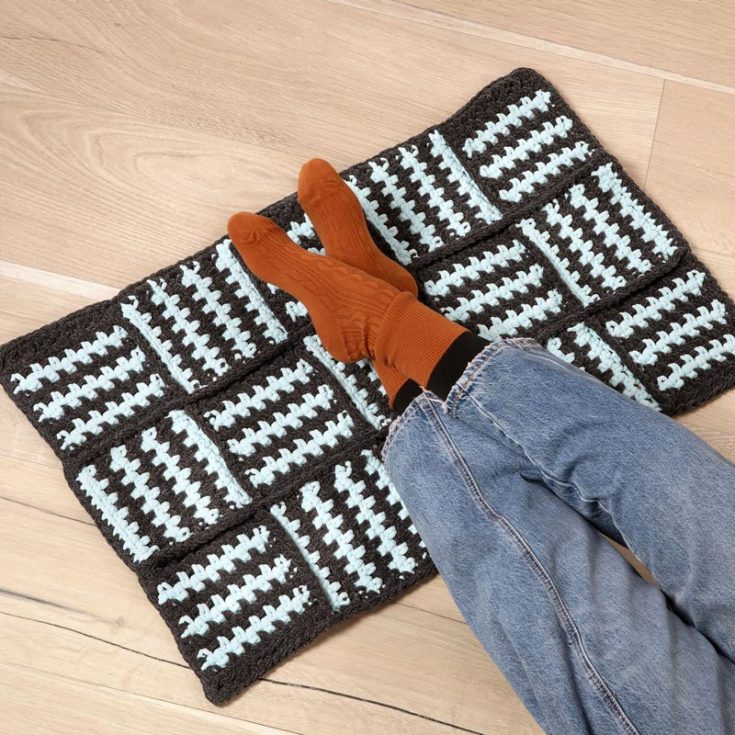 Add bold beauty to your room and make a fashion statement with this beginner-friendly crochet moss stitch square rug. It is made of striped moss stitch squares that are pieced together and simple to make!