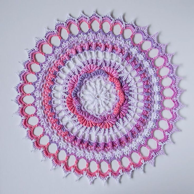 This round doily pattern gives off a sunburst effect, making it a striking addition to any space. The finished piece measures 13" in diameter and features unique stitches such as popcorn and picot, making it an intermediate-level pattern.