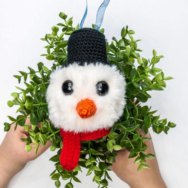 Melt anyone&rsquo;s frozen heart with this easy yet adorable fluffy crochet snowman head ornament, wearing a scarf and top hat.