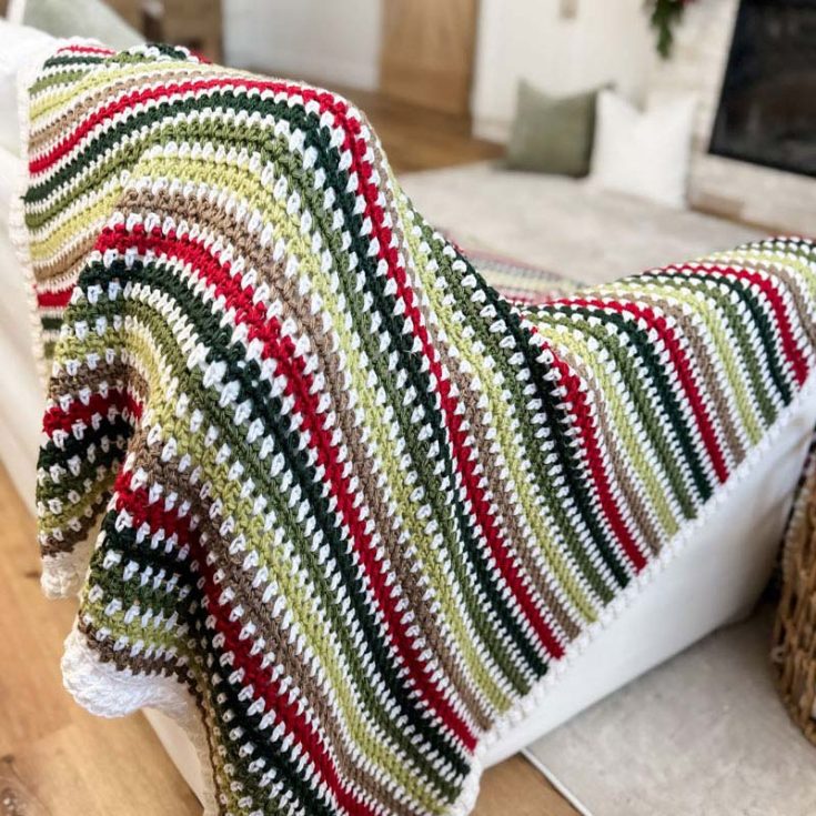 This gorgeously crafted throw incorporates the timeless moss stitch, skillfully worked in a festive palette of six stunning colors. It's an intermediate-level pattern that yields a 55&Prime; x 64&Prime; throw.